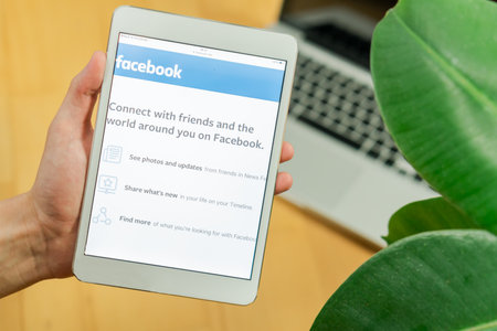 Ljubljana, Slovenia 29.4.2019: Businessman holding computer tablet with opened Facebook website and...