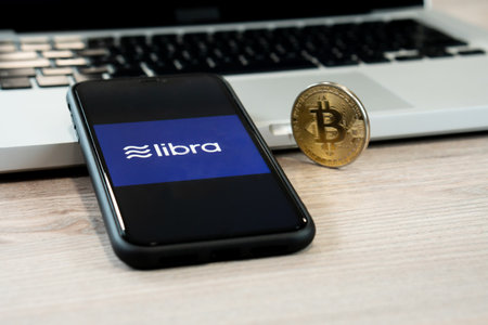18 June 2019, Ljubljana Slovenia - smartphone with Libra logo on it, next to Bitcoin coin. Facebooks new global cryptocurrency for transactionsのeditorial素材