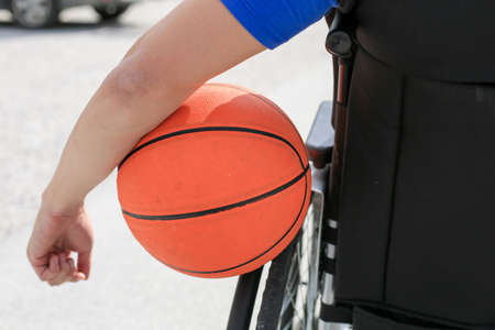 Disabled young basketball player on a wheelchair holding ball and beeing active in sportの写真素材