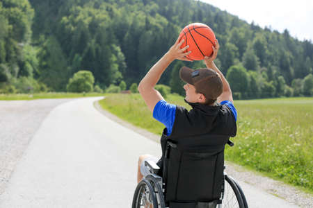 Disabled young basketball player on a wheelchair holding ball and beeing active in sportの写真素材