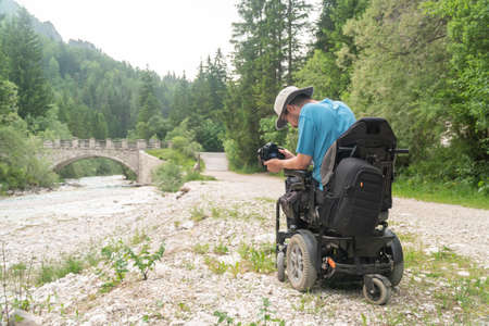 man on electric wheelchair using mirrorless camera nature, enjoying freedom and doing art