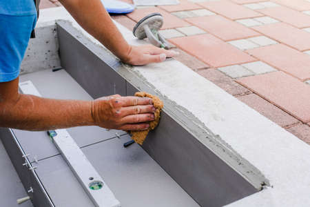 Tiler hands working on a new house entrance, local and professional handyman applying tiles to the...