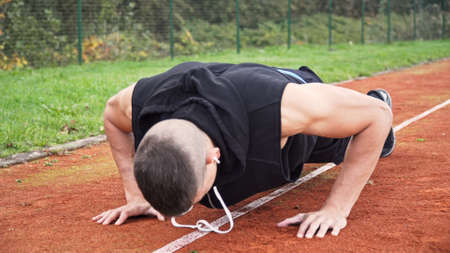Young fit man doing push ups in the morning outdoor on the running race track