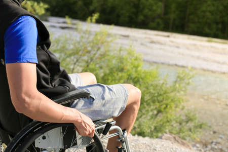 Happy young man in wheelchair outside in nature on a sunny summer dayの写真素材