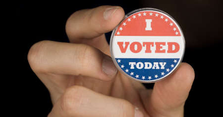 Closeup shot of a hand holding I voted today button. American elections conceptの写真素材