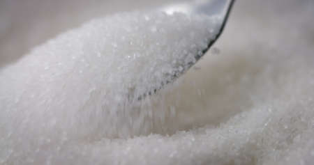 Sugar or Salt taken with Spoon from a bowl at closeup