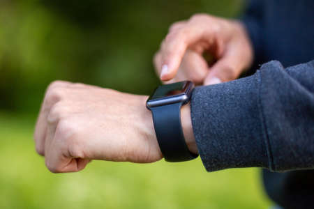 Man in nature using smartwatch app. Close-up hands
