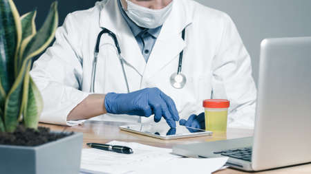 A doctor testing urine sample. Fresh specimen in a cup for examining.の素材 [FY310146342438]