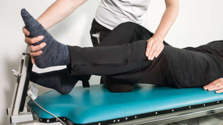 Physiotherapist exercising with disabled person on a therapy table.