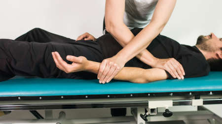 Physiotherapist exercising with disabled person on a therapy table.
