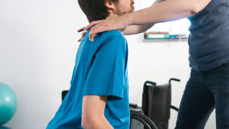 Physiotherapist exercising with disabled person using wheelchair on a therapy table.の写真素材
