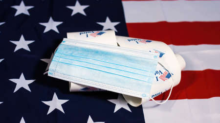 Face mask on stack of I Voted stickers for American elections on Usa flag.の写真素材