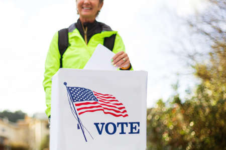 Woman voting at ballot box on american election day.