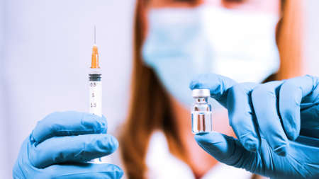 COVID-19 Coronavirus Vaccine. Doctor scientist with syringe and vial ready for injecting.の写真素材