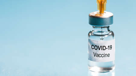 Coronavirus vaccine and syringe injection. Close-up of needle penetrating medical vial.の写真素材
