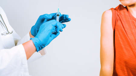 Doctor vaccinating child for Coronavirus in clinic. Syringe in a glove protected hands.の写真素材