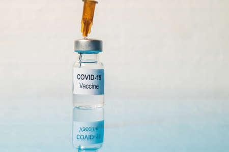 Coronavirus vaccine and syringe injection. Close-up of needle penetrating medical vial.の写真素材