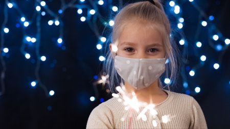 Cheerful child girl with Sparkler in hand celebrating Coronavirus new year.の写真素材