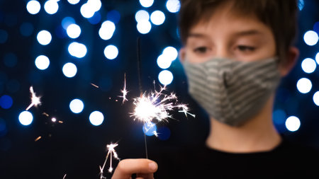 Portrait of boy child celebrating new year wearing a face mask at coronavirus pandemic.の写真素材