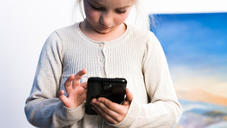 Cute little girl looking and playing with smartphone.