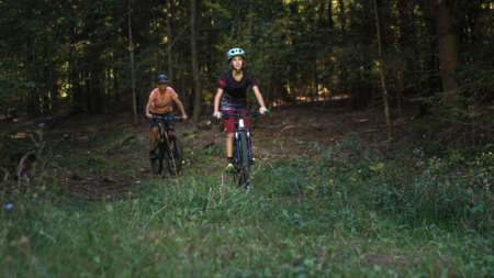 Two girls on mtb bikes. Mother and daughter riding on a forest trail.