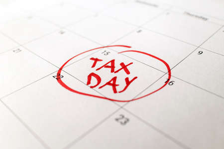 Tax day marked on April 15 calendar with red marker. Deadline for 1040 form return.の写真素材