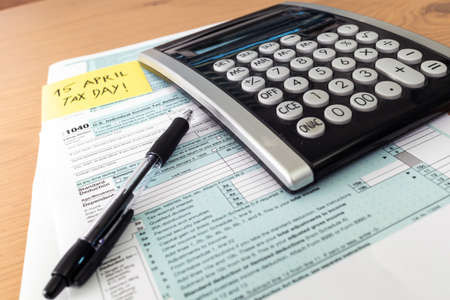 Tax day. 1040 form and calculator on table ready to be filled and returned.の写真素材