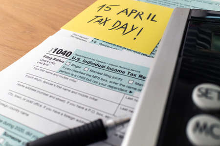 Tax day. 1040 form and calculator on table ready to be filled and returned.の写真素材