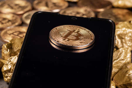 Bitcoin cryptocurrency on smartphone with gold nuggets. Investment and store of value concept.の写真素材