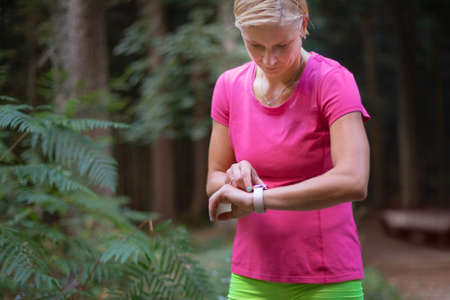 Middle shot of a Caucasian woman adjusting a smartwatch before running