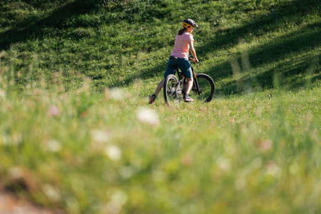 Woman riding mountain bike on a green meadow in summer.の写真素材