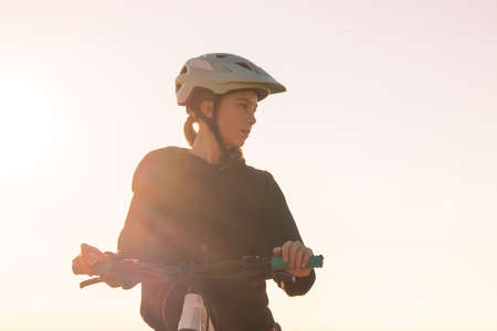 Girl child riding mountain bike at sunset. Beautiful golden summer light.の写真素材