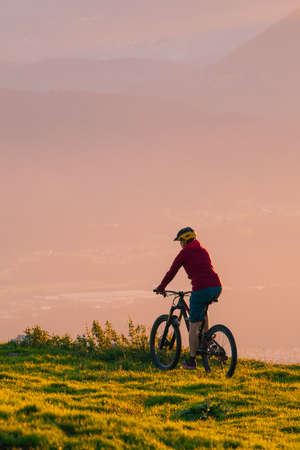 Woman riding mountain bike into the sunset. Beautiful golden summer light.の写真素材