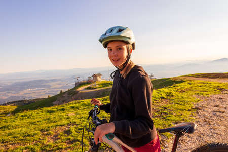 Girl child riding mountain bike into the sunset. Beautiful golden summer light.の写真素材