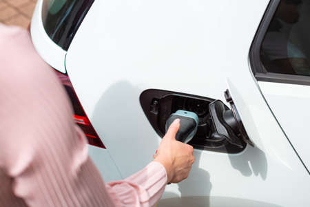 Woman charging an electric car with power supply cable.の写真素材