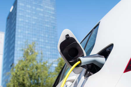 Charging an electric car in city with power supply cable.