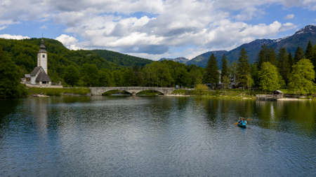 Aerial bird eye shot of a canoe with two person paddling, on beautiful turquoise lake waterの写真素材