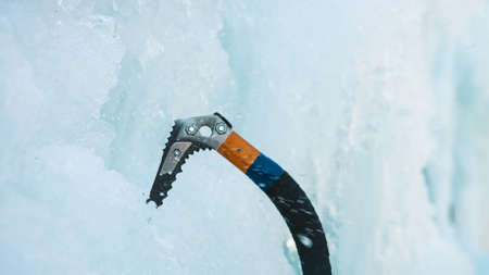 Point of view ice climber swinging the ice axe into the vertical ice covered surfaceの写真素材