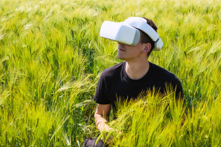 Man using virtual reality glasses outside in nature on a wheat farming field.