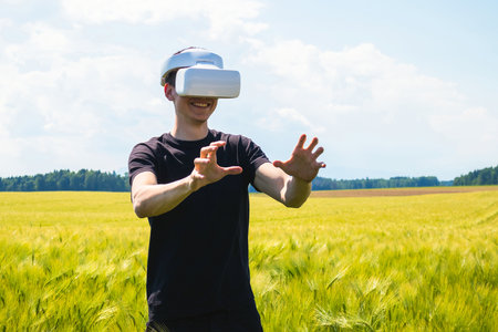 Man using virtual reality glasses outside in nature on a wheat farming field.