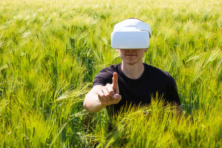 Man using virtual reality glasses outside in nature on a wheat farming field.の写真素材