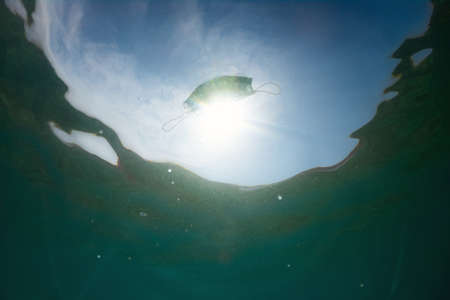 Ocean pollution with face masks. Overuse during the coronavirus pandemic.