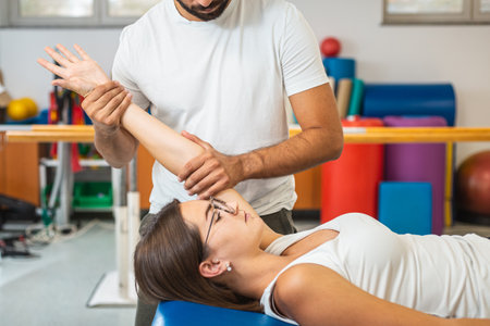 Male hysiotherapist doing elbow extension exercises with a young female patient at a clinicの写真素材