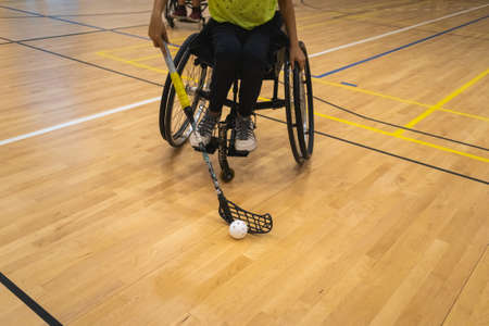 Athlete with disability playing wheelchair hockey with stick.