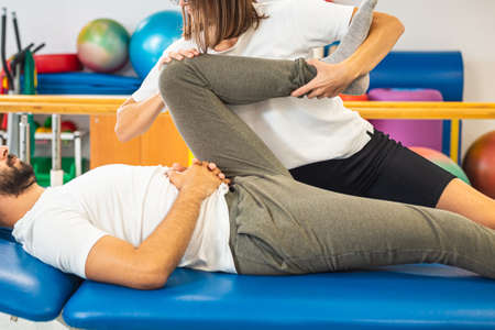 Female physiotherapist doing a treatment for the mobility of the male patient knees and hips.