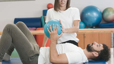 Female physiotherapist and male patient during rehabilitation therapy. Ccore strengthening exercises...