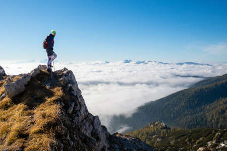Woman on top of the mountain above the clouds bathing in sunlight.の写真素材