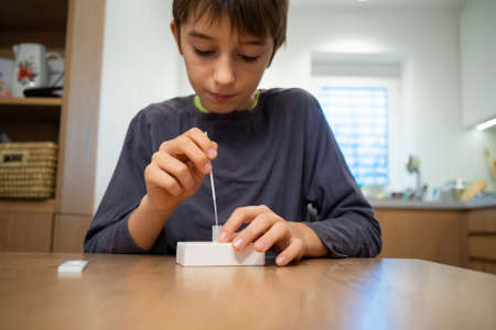 Child self testing for coronavirus at home before going to school.の写真素材