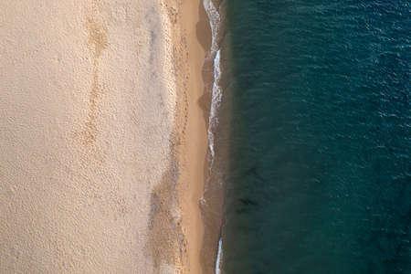 Aerial top down view of beautiful white sand beach bathed by clear turquoise seawater.の写真素材