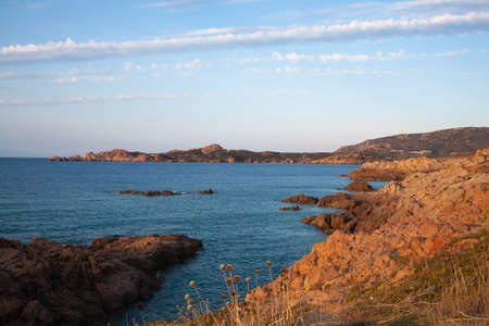 Aerial shot of a rocky shoreline and tranquil seawater beautiful shining in the sun. Drone flying between rock formations.の写真素材